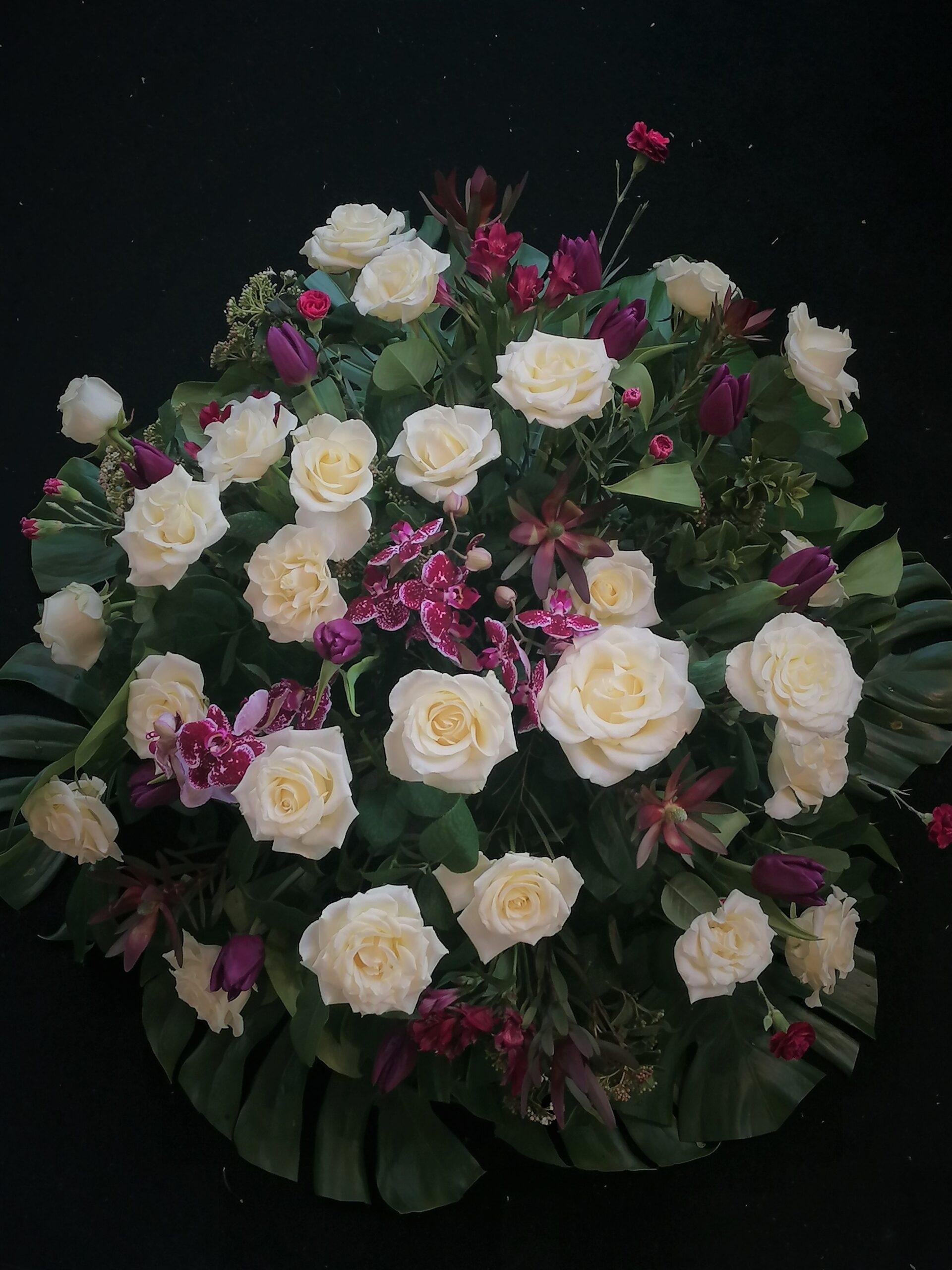 The wreath abounds with tulips, alstromeria, orchids, carnations and leucadendrons.