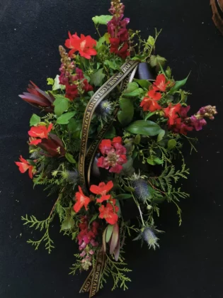 This is an elegant, dark-coloured composition made of burgundy, red alstroemerias and anole and an accent of blue eryngium flowers.