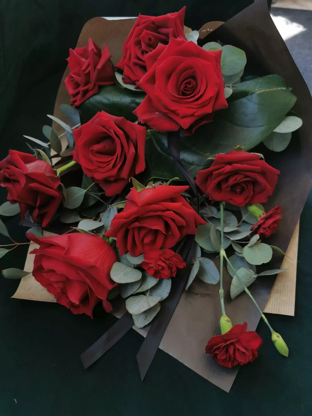 An elegant, minimalist form of bouquet. Roses of large, strong in colour and size surrounded by eucalyptus greenery and black paper with a symbolic ribbon.