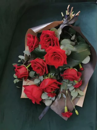 Elegancka, minimalistyczna forma bukietu. Róże o dużym, mocnym w kolorze i wielkości kształcie w otoczeniu eukaliptusowej zielni oraz czarnego papieru z symboliczną wstążki.