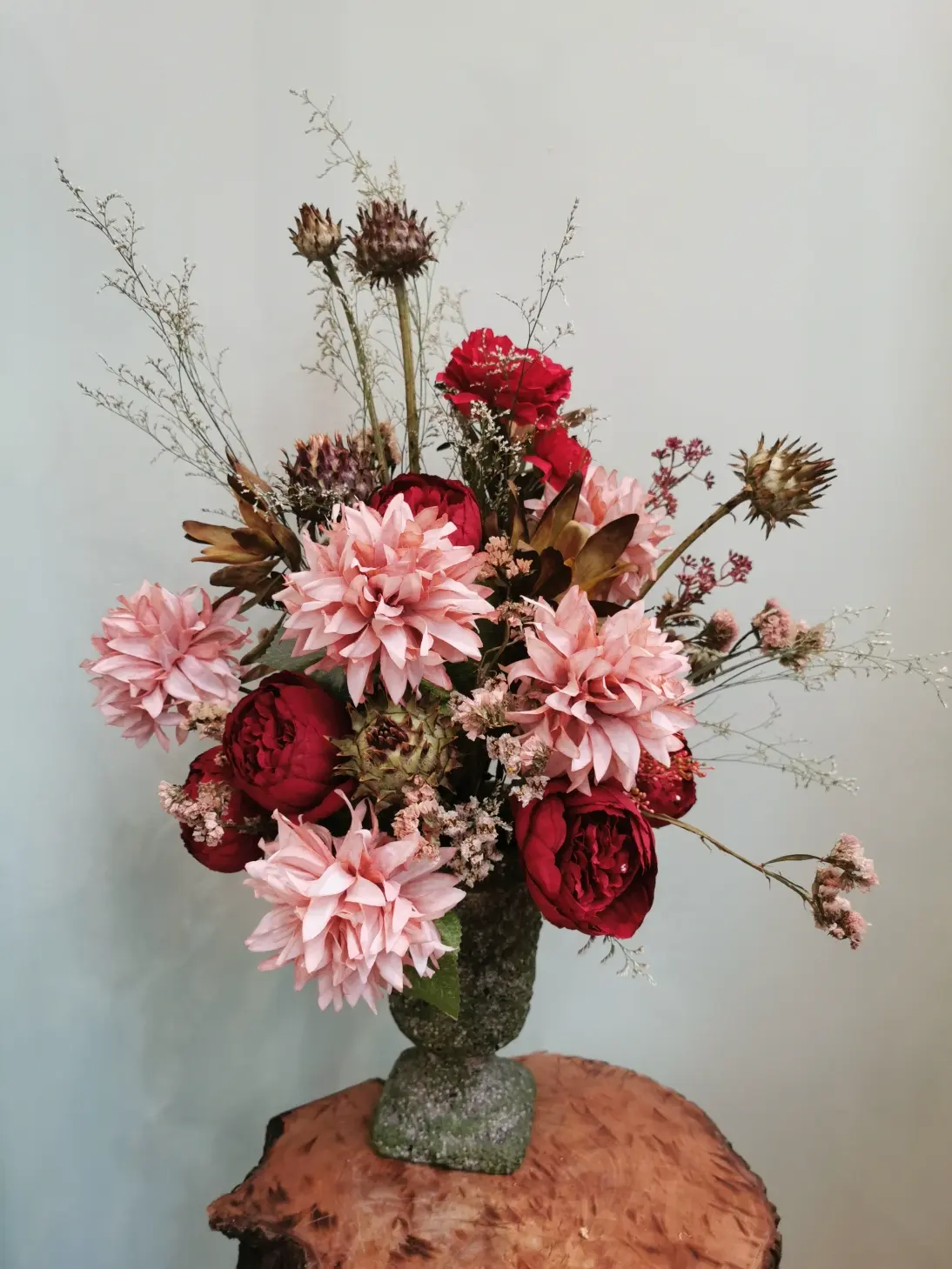Te dekoracja łączy ze sobą kwiaty sztuczne: kremowe pełne dalie oraz strzeliste filigranowe gąłazki.