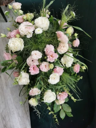 Subtelna, pastelowa kolorystyka w formie kompozycji w kształcie kropli, wykonana z pudrowo – różowych eustom i róż