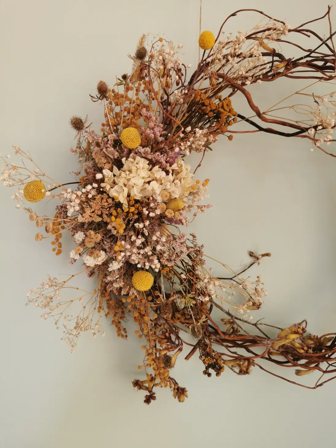 A subtle, space-age proposal for a garland on a wicker hoop with a brooch to the left.