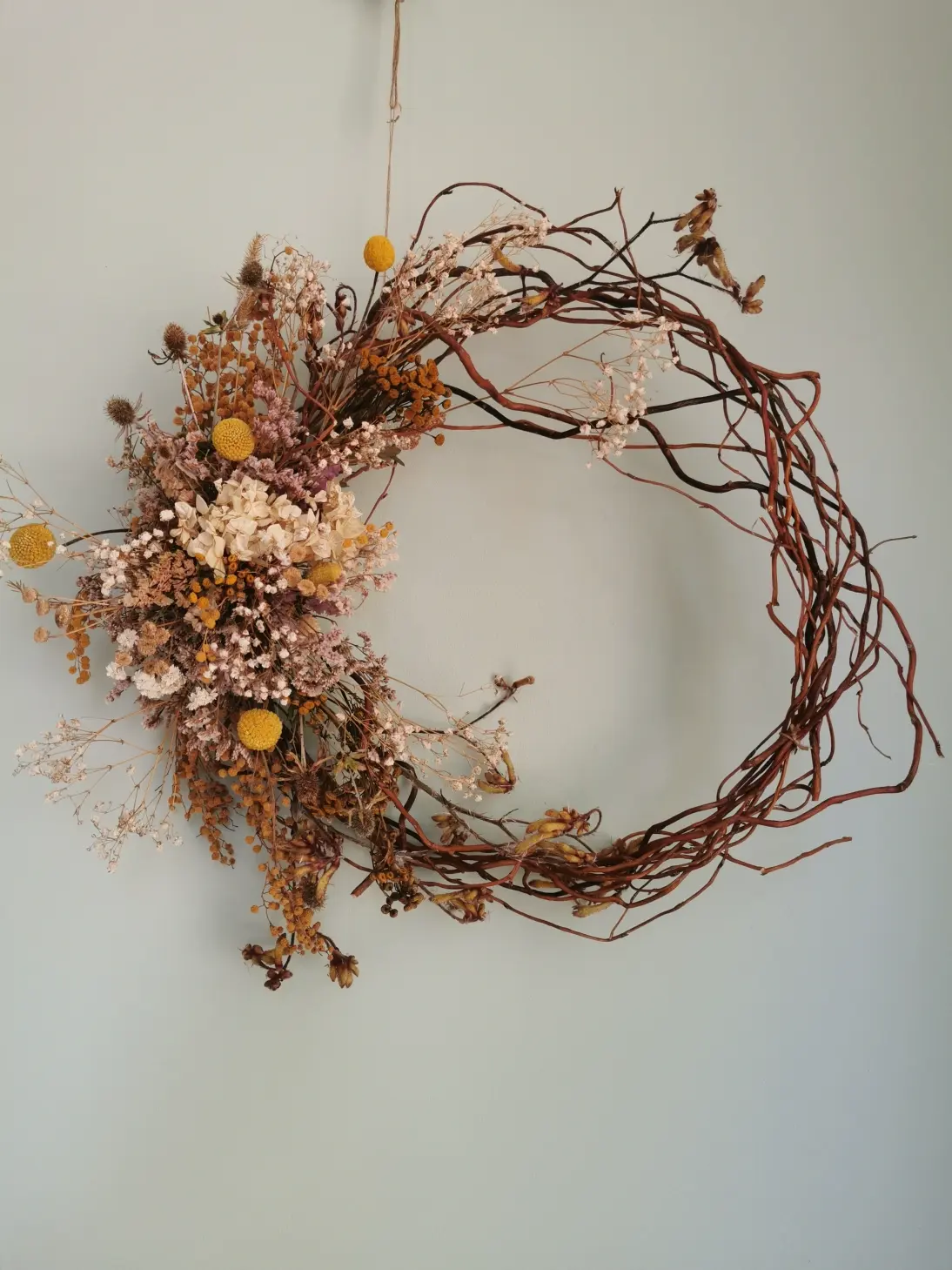 A subtle, space-age proposal for a garland on a wicker hoop with a brooch to the left.