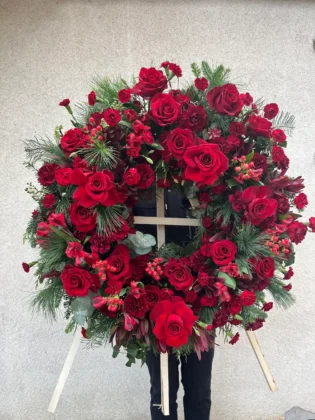 Wieniec rzymski w czerwieni z czerwonych róż i zieleni dekoracyjnej