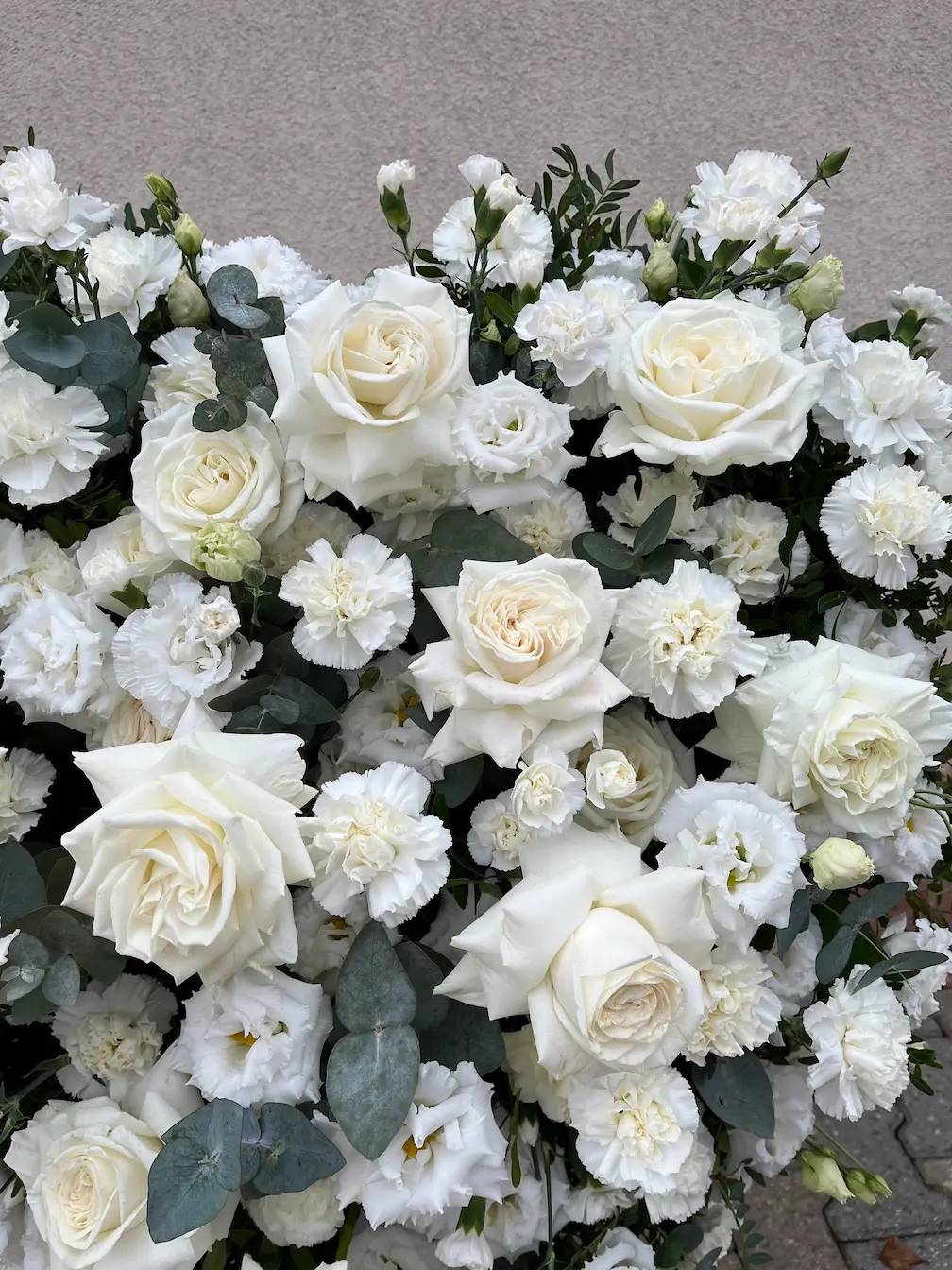 Detal kompozycji florystycznej – wieniec serce w bieli Detal wieńca serce w bieli – białe róże i drobne kwiaty w kompozycji pogrzebowej